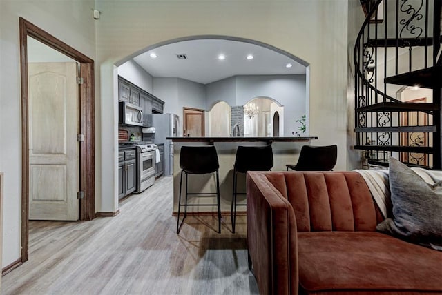 17009 Picasso Dr, Oklahoma City, OK 73170 - kitchen featuring stainless steel appliances, arched walkways, light wood-style flooring, a kitchen breakfast bar, and recessed lighting