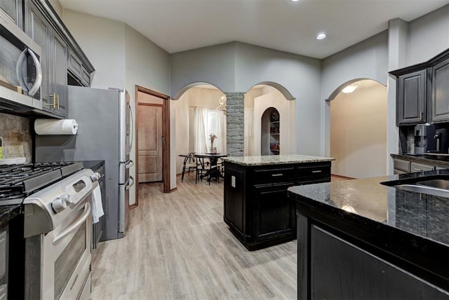 17009 Picasso Dr, Oklahoma City, OK 73170 - kitchen with arched walkways, stainless steel appliances, decorative backsplash, light wood-type flooring, and recessed lighting