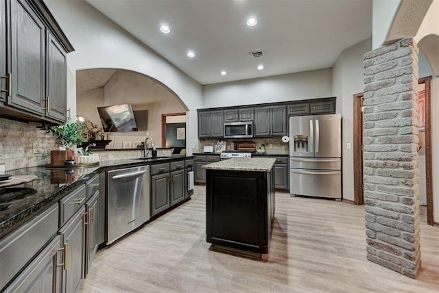 17009 Picasso Dr, Oklahoma City, OK 73170 - kitchen featuring stainless steel appliances, a sink, arched walkways, tasteful backsplash, and light wood-style floors