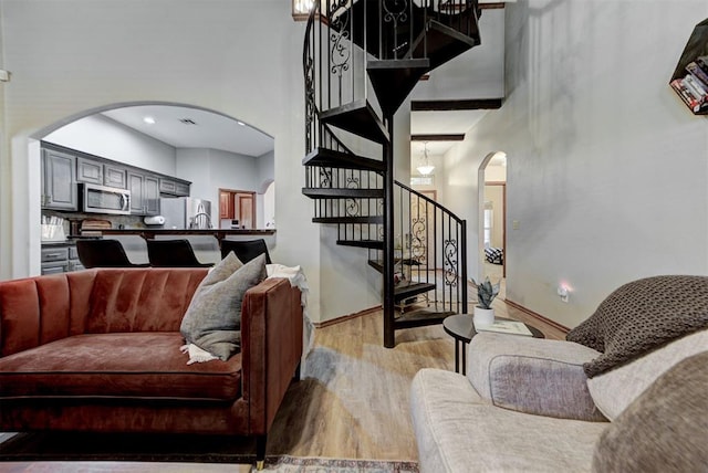 17009 Picasso Dr, Oklahoma City, OK 73170 - living area featuring arched walkways, a towering ceiling, light wood-type flooring, stairs, and baseboards