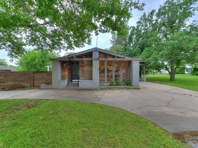 mid-century home with driveway, brick siding, and covered porch