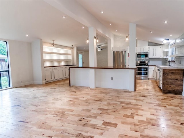 kitchen featuring appliances with stainless steel finishes, open floor plan, dark countertops, white cabinets, and ceiling fan