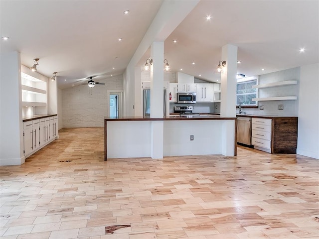kitchen featuring appliances with stainless steel finishes, dark countertops, open floor plan, a ceiling fan, and open shelves