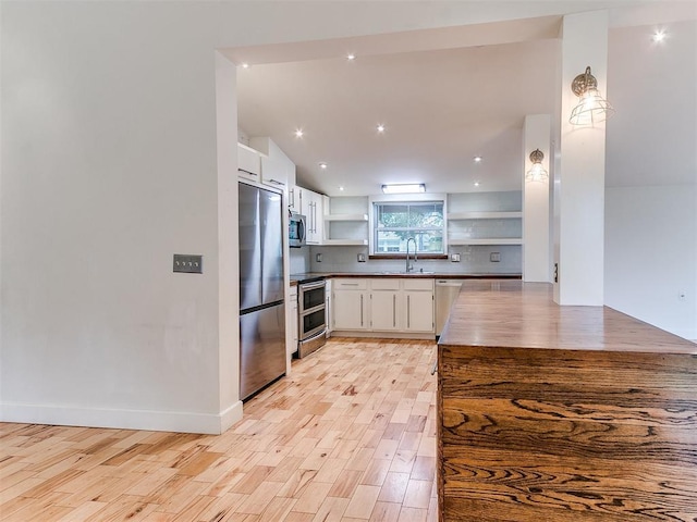 kitchen with open shelves, stainless steel appliances, a sink, white cabinets, and light wood-style floors