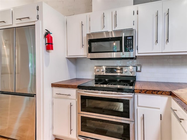 kitchen featuring appliances with stainless steel finishes, dark countertops, decorative backsplash, and white cabinets