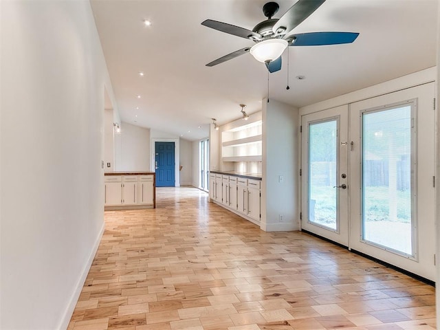 empty room with baseboards, french doors, lofted ceiling, ceiling fan, and light wood finished floors