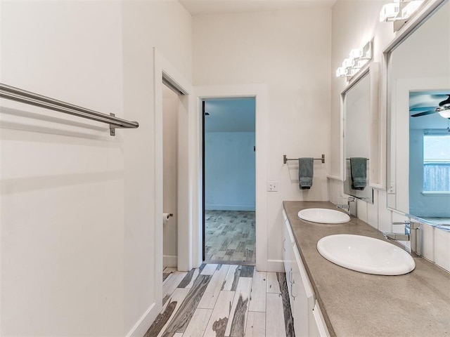 full bath with ceiling fan, double vanity, and wood finished floors