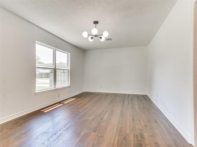 213 E Haddock St, Norman, OK 73069 - spare room featuring a chandelier, wood finished floors, a textured ceiling, and baseboards