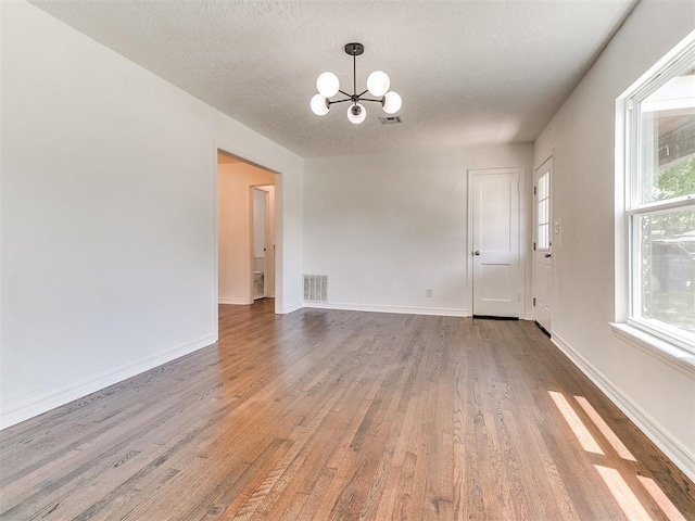213 E Haddock St, Norman, OK 73069 - empty room featuring a chandelier, wood finished floors, a textured ceiling, and baseboards