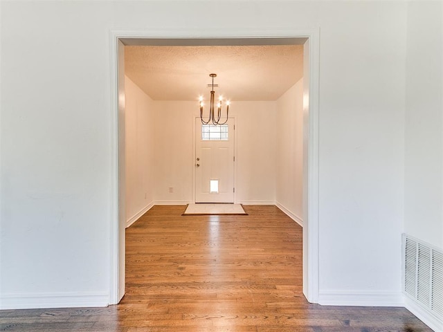 213 E Haddock St, Norman, OK 73069 - entrance foyer with a chandelier, wood finished floors, baseboards, and a textured ceiling