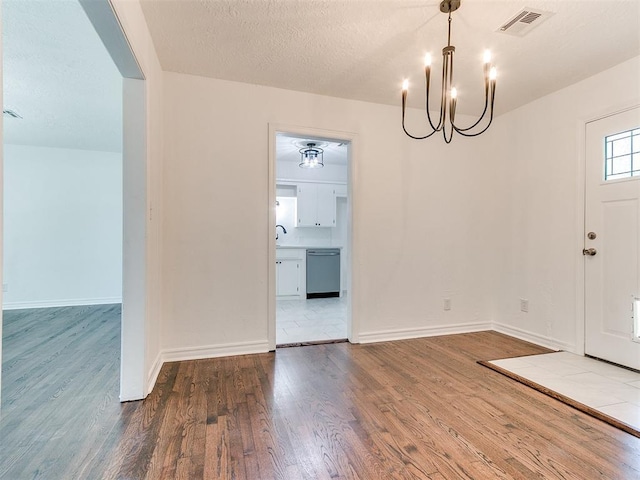213 E Haddock St, Norman, OK 73069 - entrance foyer with a chandelier, wood finished floors, baseboards, and a textured ceiling