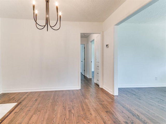 213 E Haddock St, Norman, OK 73069 - spare room with wood finished floors, a chandelier, and baseboards