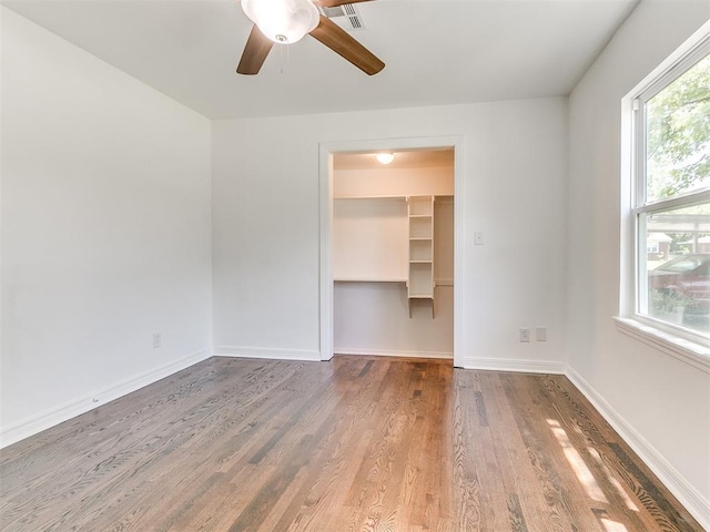 213 E Haddock St, Norman, OK 73069 - unfurnished bedroom featuring wood finished floors, a spacious closet, baseboards, a closet, and ceiling fan