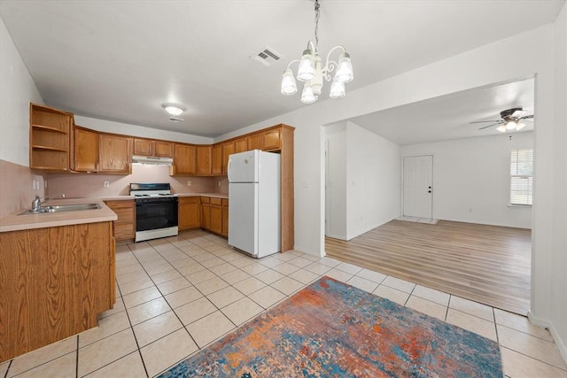 236 NW 91st St, Oklahoma City, OK 73114 - kitchen with freestanding refrigerator, range with gas stovetop, light tile patterned floors, under cabinet range hood, and light countertops