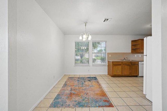 236 NW 91st St, Oklahoma City, OK 73114 - unfurnished dining area featuring light tile patterned flooring, a chandelier, a sink, and baseboards