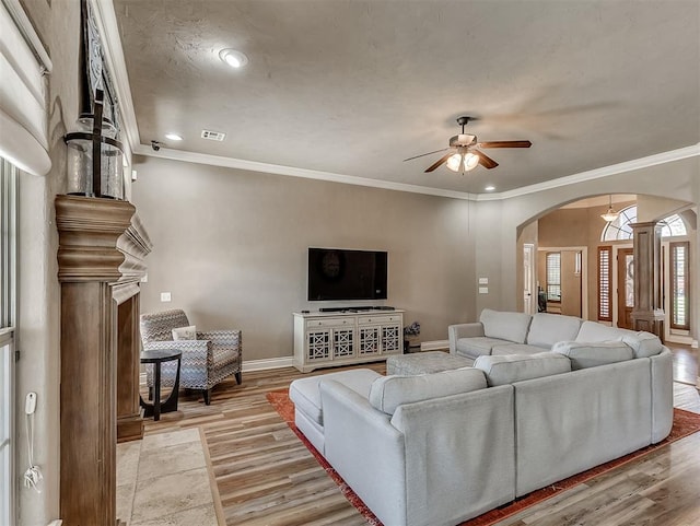12515 Forest Oaks Dr, Choctaw, OK 73020 - living room featuring arched walkways, ceiling fan, light wood-style flooring, decorative columns, and crown molding