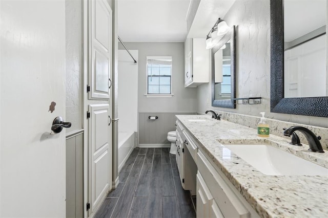 1500 S Railroad, Marlow, OK 73055 - full bathroom featuring double vanity, wood finished floors, bathing tub / shower combination, toilet, and a wainscoted wall