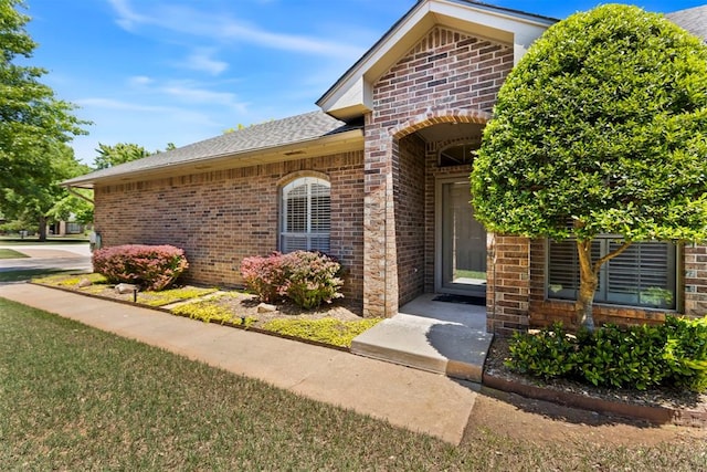 property entrance with brick siding and a shingled roof