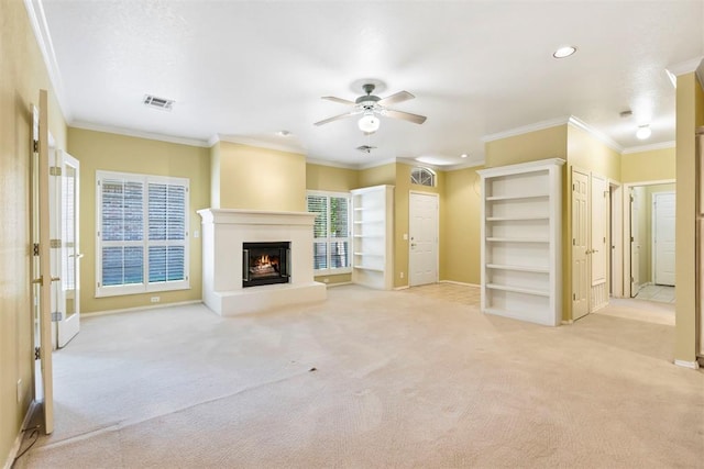 unfurnished living room with carpet, a ceiling fan, a warm lit fireplace, ornamental molding, and baseboards