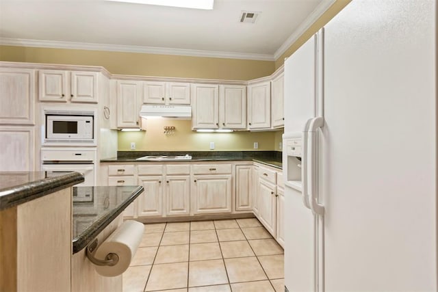 kitchen with white appliances, under cabinet range hood, ornamental molding, light tile patterned flooring, and dark stone counters