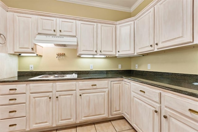 kitchen featuring under cabinet range hood, crown molding, white electric stovetop, light tile patterned floors, and dark stone counters