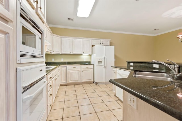 kitchen with white appliances, a sink, ornamental molding, light tile patterned floors, and white cabinets
