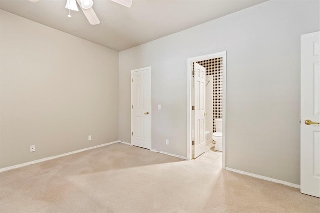 unfurnished bedroom featuring light colored carpet, baseboards, ensuite bathroom, and ceiling fan