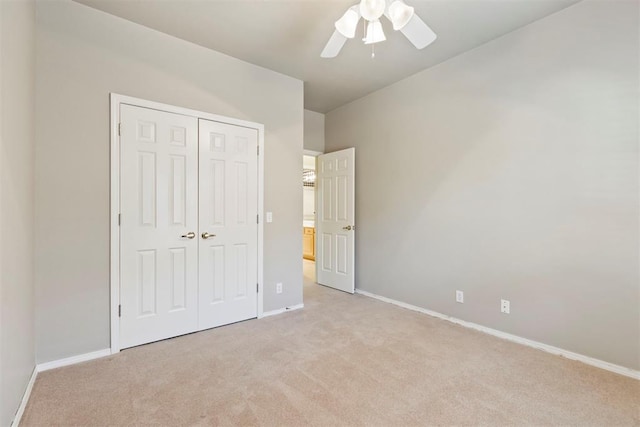 unfurnished bedroom featuring light colored carpet, a closet, and baseboards