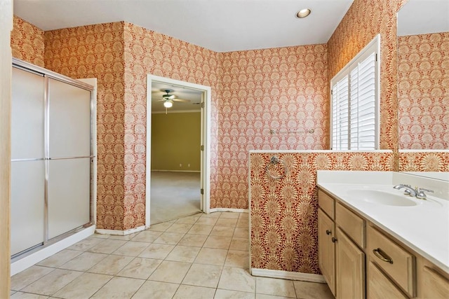 bathroom featuring a shower stall, baseboards, a ceiling fan, wallpapered walls, and vanity