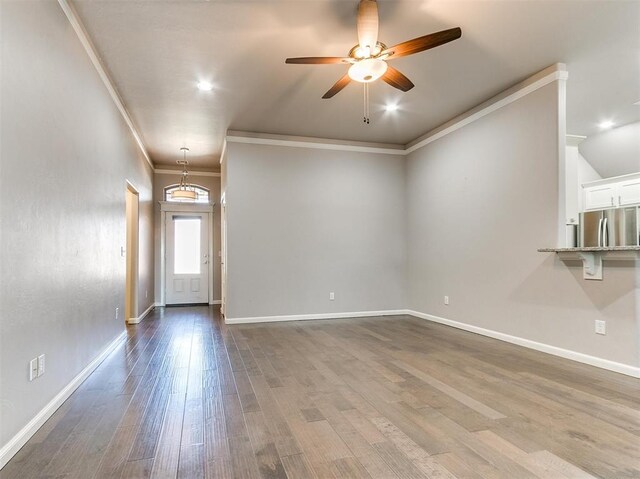 2408 Santa Monica St, Edmond, OK 73034 - unfurnished living room featuring ceiling fan, dark wood-style floors, crown molding, and baseboards