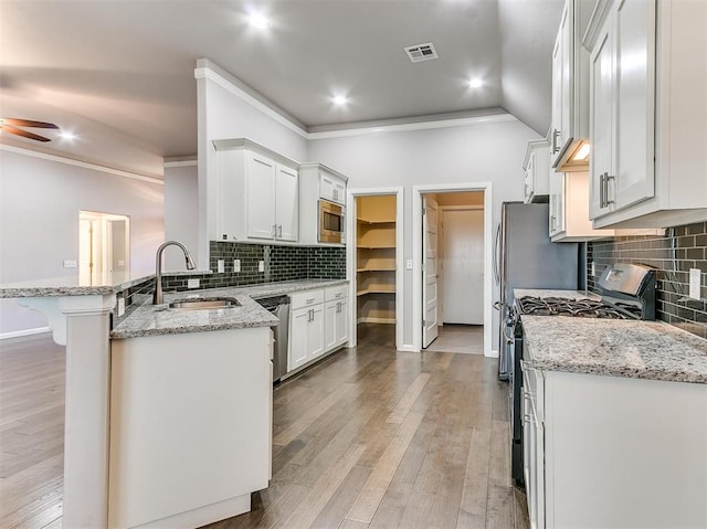 2408 Santa Monica St, Edmond, OK 73034 - kitchen with stainless steel appliances, a sink, a peninsula, tasteful backsplash, and ornamental molding