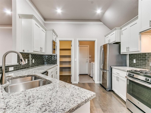 2408 Santa Monica St, Edmond, OK 73034 - kitchen with appliances with stainless steel finishes, a sink, independent washer and dryer, crown molding, and white cabinets