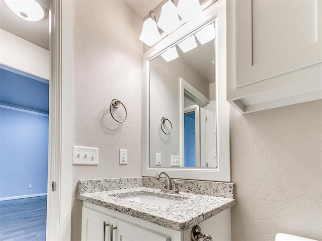 2408 Santa Monica St, Edmond, OK 73034 - half bath featuring vanity, wood finished floors, a textured wall, and baseboards