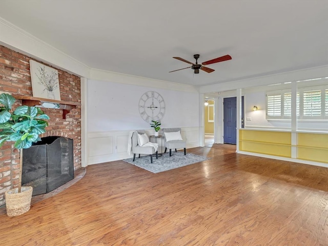 6120 Kingston Rd, Oklahoma City, OK 73122 - unfurnished living room with ceiling fan, wood finished floors, crown molding, a brick fireplace, and wainscoting