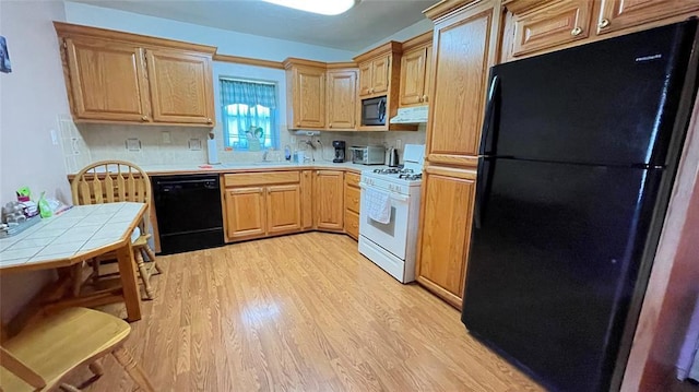 123 S 4th St, Sentinel, OK 73664 - kitchen with black appliances, tile countertops, light wood finished floors, range hood, and light brown cabinets