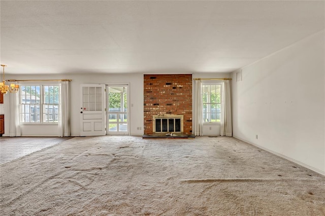 unfurnished living room with carpet flooring, plenty of natural light, and a chandelier