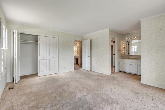 unfurnished bedroom with ornamental molding, light carpet, a closet, and ensuite bath