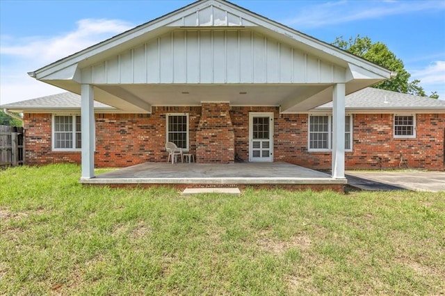 rear view of property with a patio, brick siding, and board and batten siding