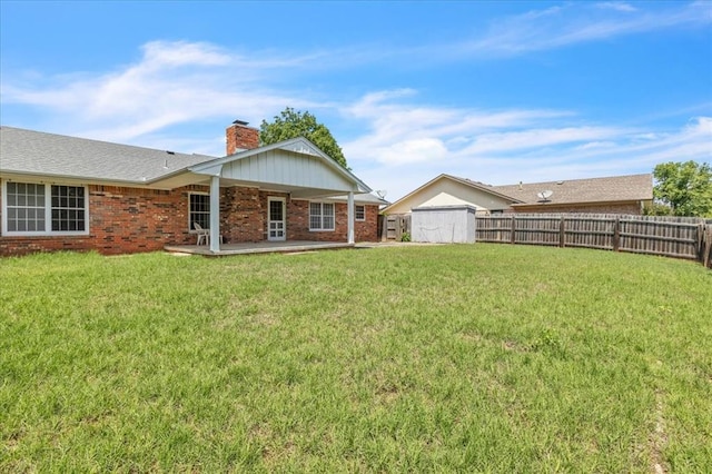 back of house with a chimney, brick siding, a patio area, a shed, and an outdoor structure