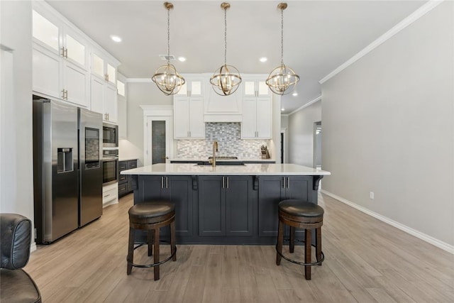 kitchen with stainless steel appliances, light countertops, tasteful backsplash, ornamental molding, and white cabinets