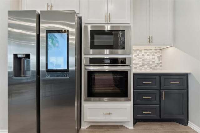 kitchen with appliances with stainless steel finishes, white cabinetry, light countertops, light wood finished floors, and decorative backsplash