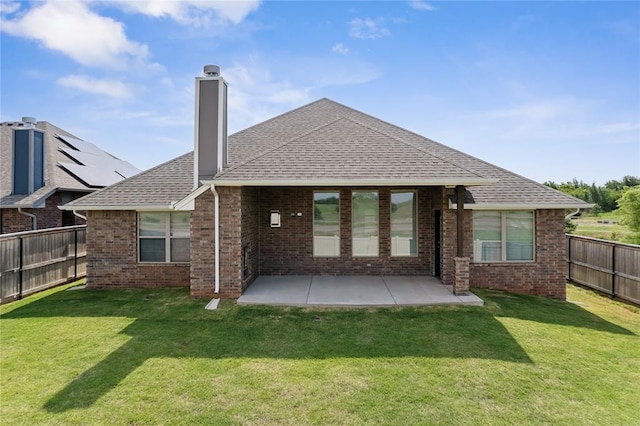 back of property featuring a chimney, brick siding, a patio, and roof with shingles