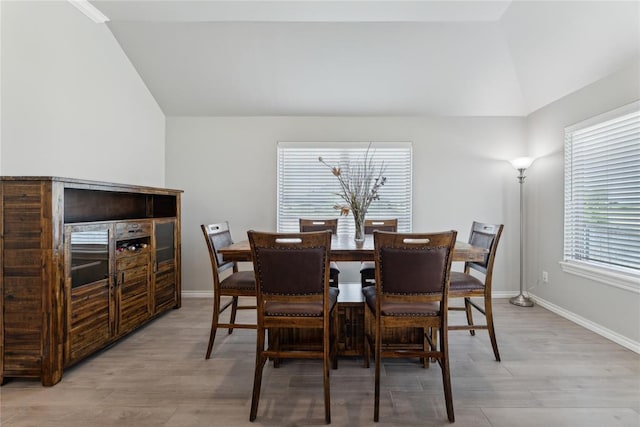 dining space featuring vaulted ceiling, light wood finished floors, and baseboards