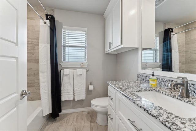 bathroom with marble finish floors, toilet, vanity, shower / tub combo, and baseboards