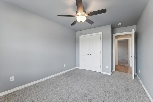 unfurnished bedroom with carpet, a closet, baseboards, and ceiling fan