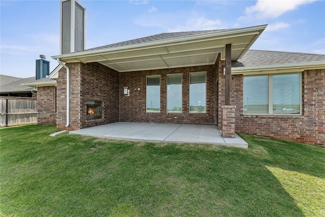 back of property featuring a chimney, brick siding, a fireplace, and a patio