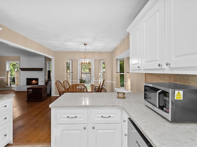 2113 Castle Rock, Edmond, OK 73003 - kitchen featuring stainless steel appliances, a brick fireplace, a peninsula, and light stone countertops