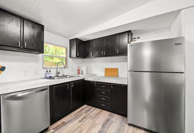 168 Bobber Rd, Broken Bow, OK 74728 - kitchen featuring stainless steel appliances, dark cabinets, light countertops, a sink, and light wood-type flooring