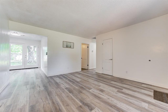 1316 W Logan Ave, Guthrie, OK 73044 - unfurnished living room featuring light wood-style flooring, baseboards, and french doors