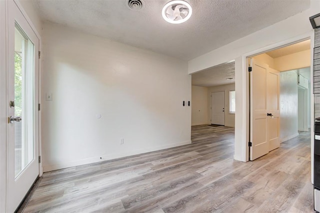 1316 W Logan Ave, Guthrie, OK 73044 - unfurnished room with light wood-type flooring, a textured ceiling, and baseboards